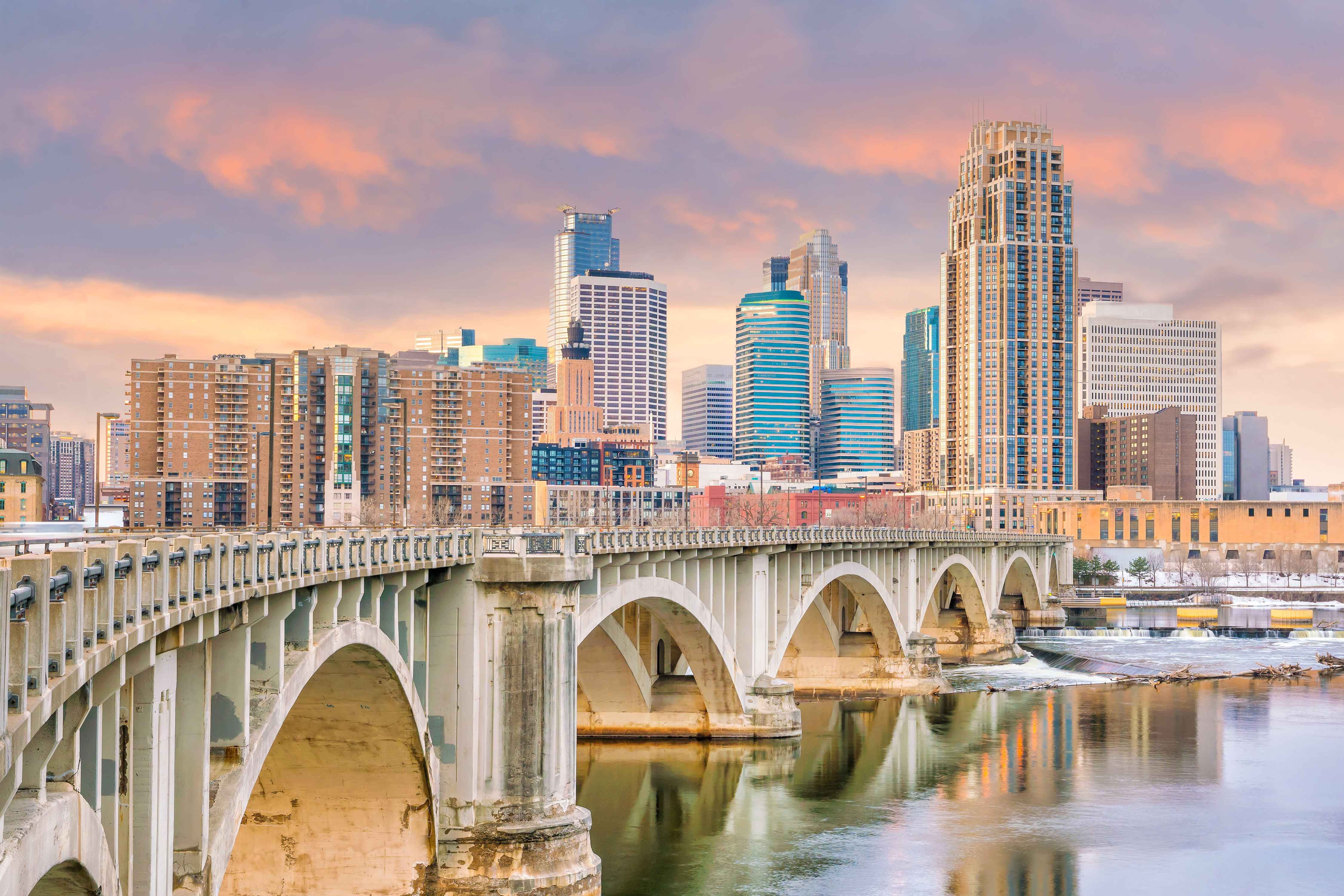 Minneapolis skyline and Stone Arch Bridge over Mississippi River at sunset